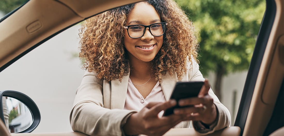 Smiling Woman Holding Phone At Car Window