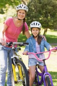 Middle-Aged Woman and Young Girl Smile at the Camera while Sitting on Their Bicycles