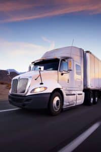 Semi-truck with trailer driving down the highway.
