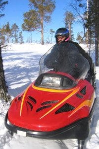 Individual Driving a Red Snowmobile