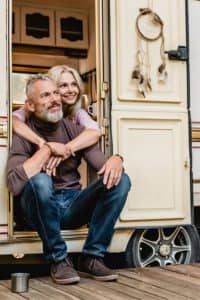 Happy couple sitting in the doorway of their motor home.