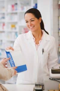 Pharmacist handing customer a prescription in a drug store.