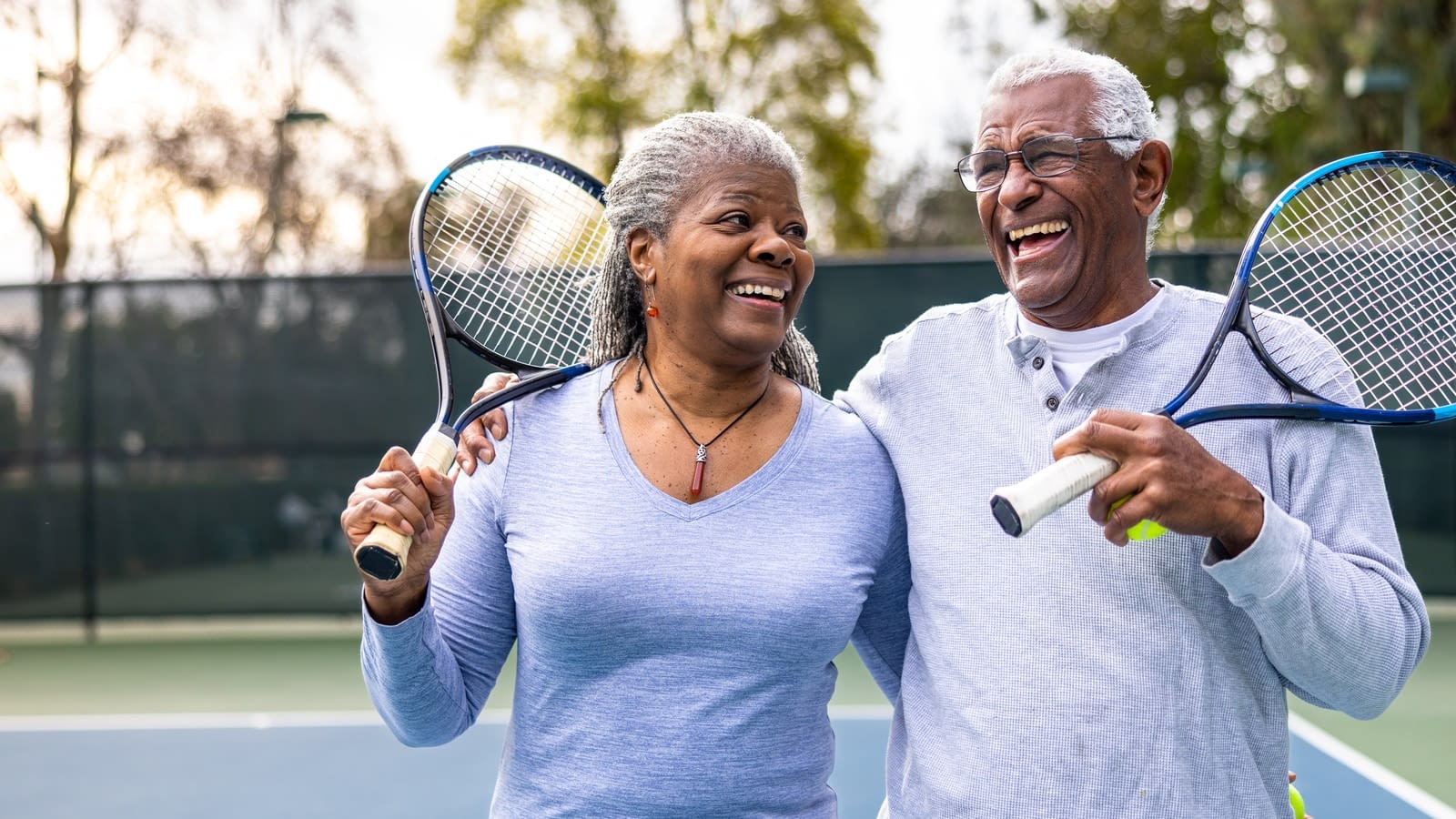 healthy seniors senior couple walking off the tennis court with rackets