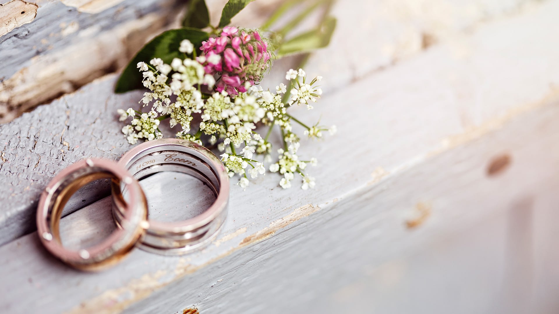 Two wedding bands next to decorative flowers.