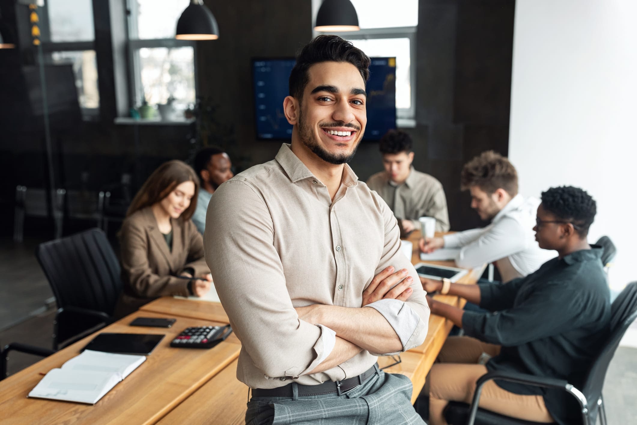 GettyImages-1322913815 Smiling Young Businessman Sitting on Desk