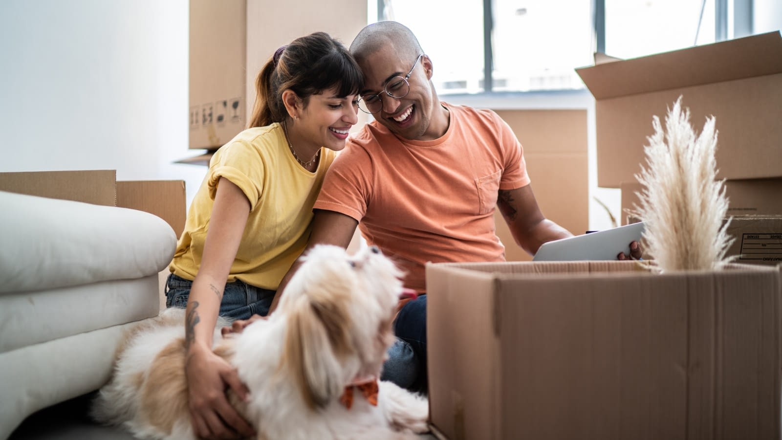 Young couple smiling at dog Young couple on the floor of new home