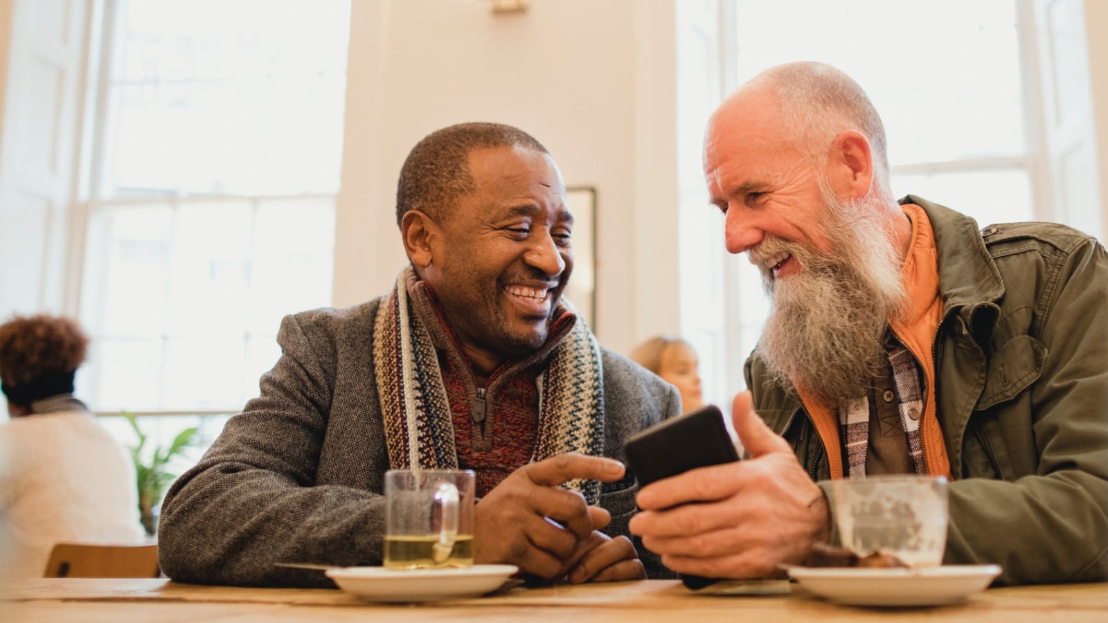 ship two senior men talking and laughing while sitting in a restaurant