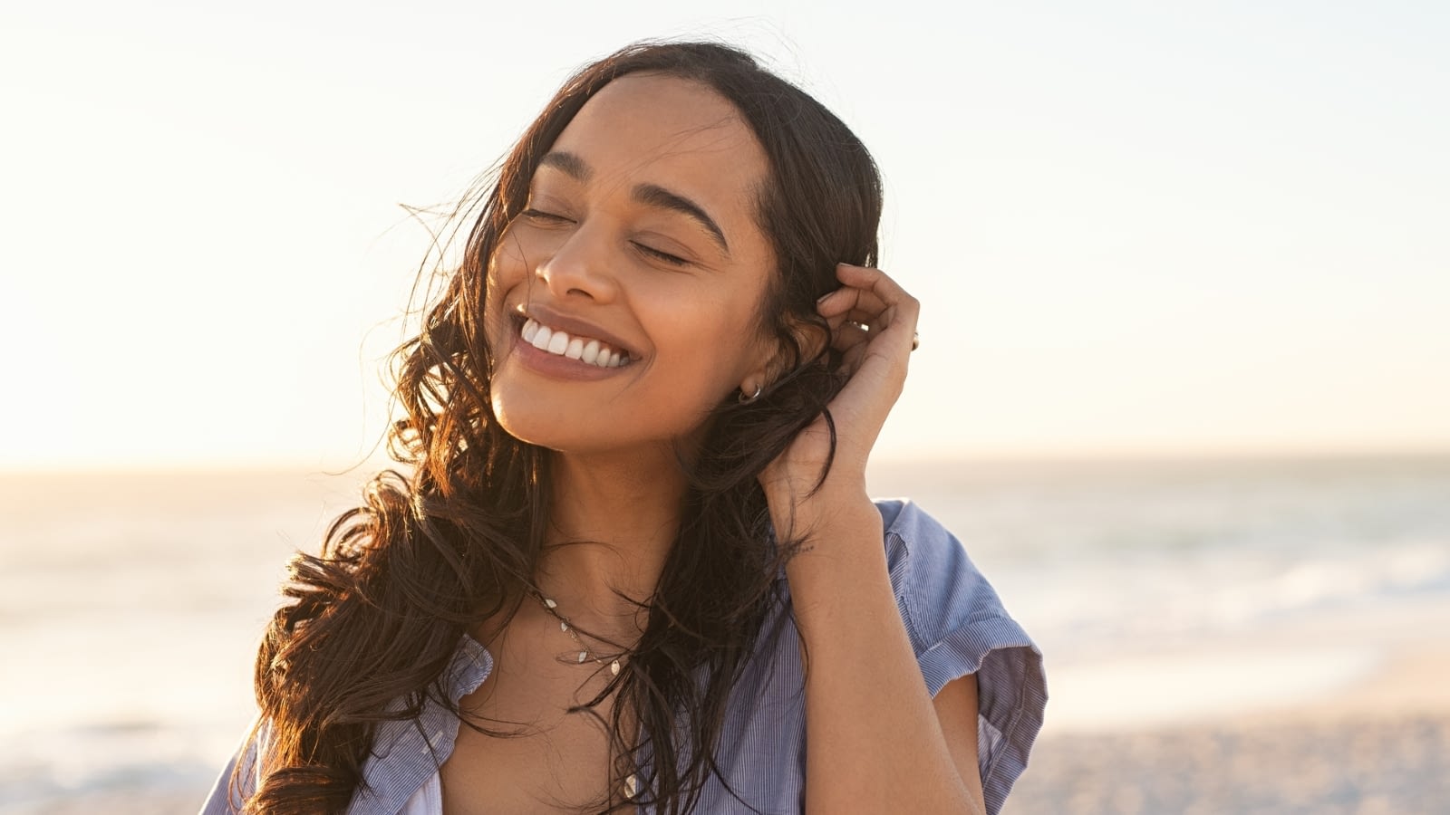 young woman smiling with eyes closed at the beach
