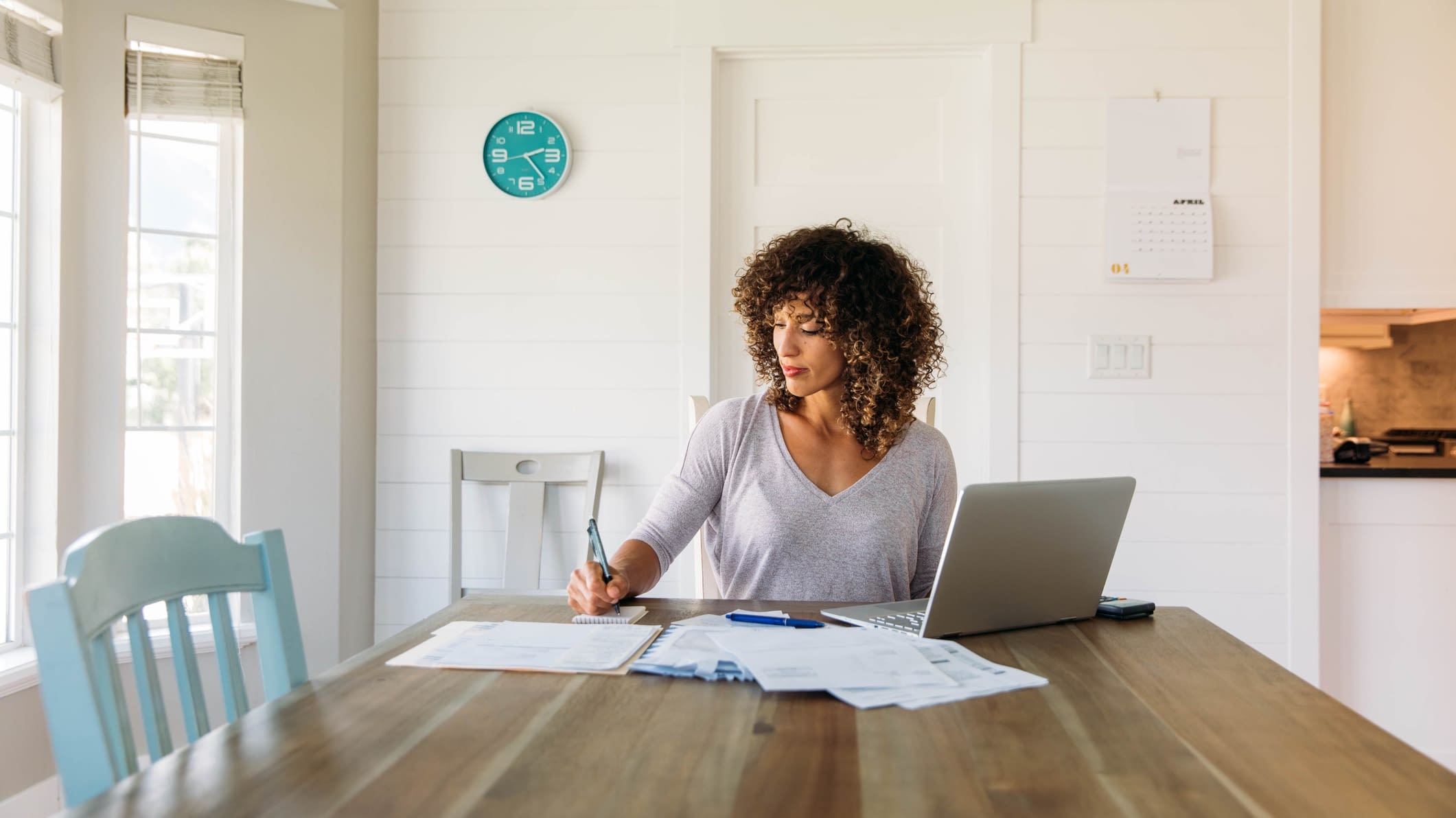 Woman looking at important papers Woman at kitchen table looking at documents