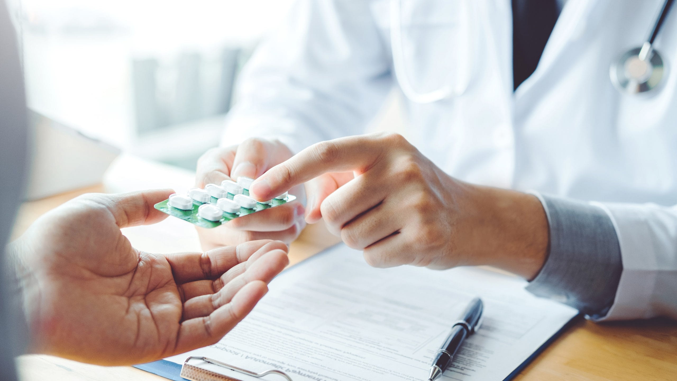 Close-up of pharmacist explaining medication to a patient.