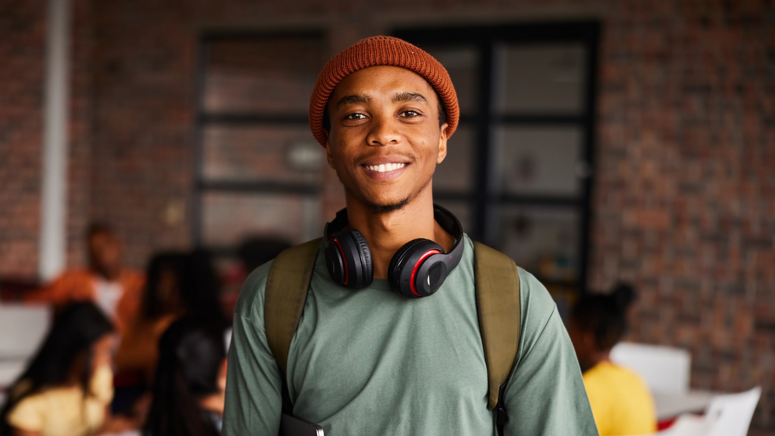 Smiling college student holding a laptop.