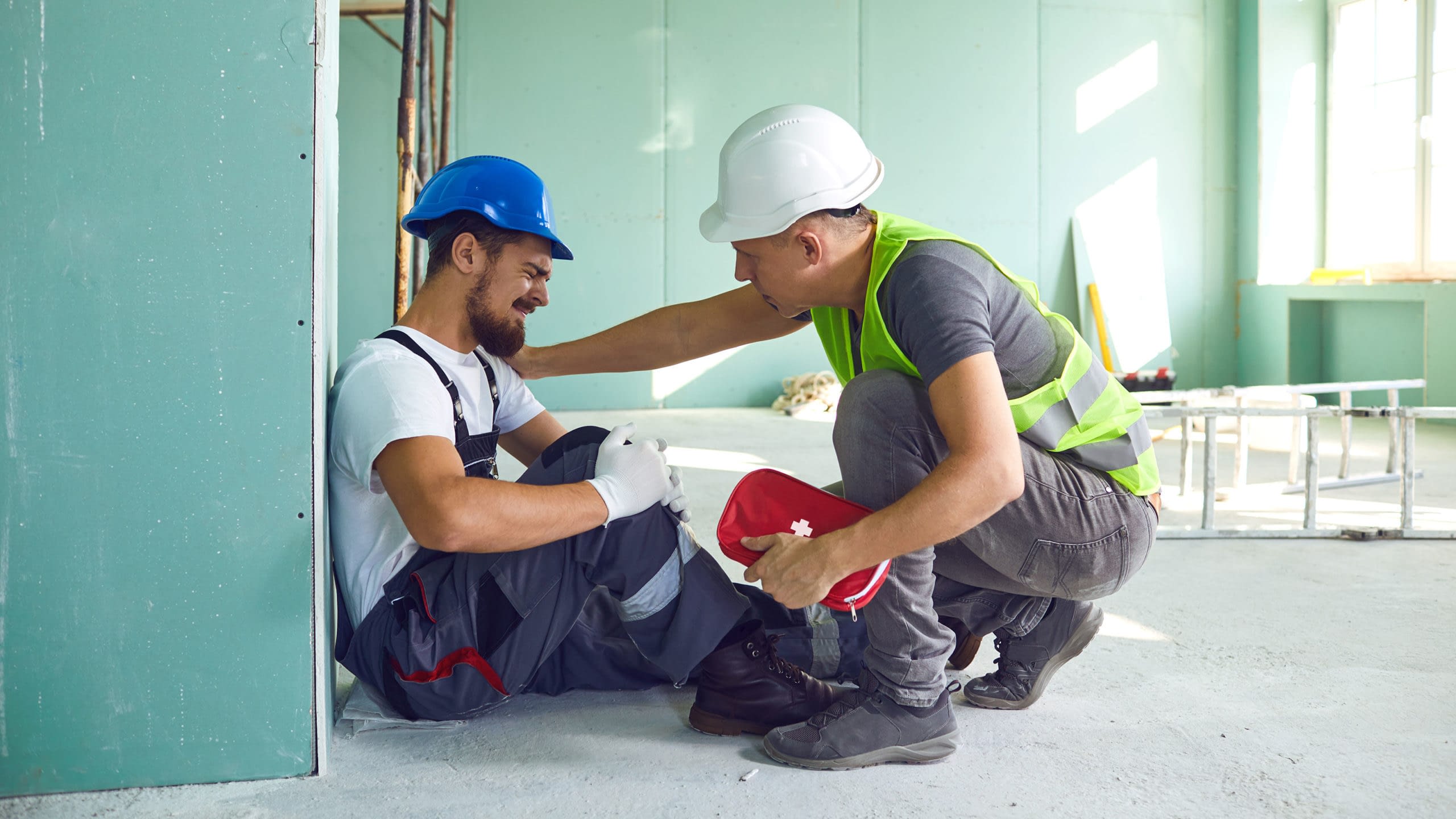 Construction worker tending to injured co-worker on a job site.