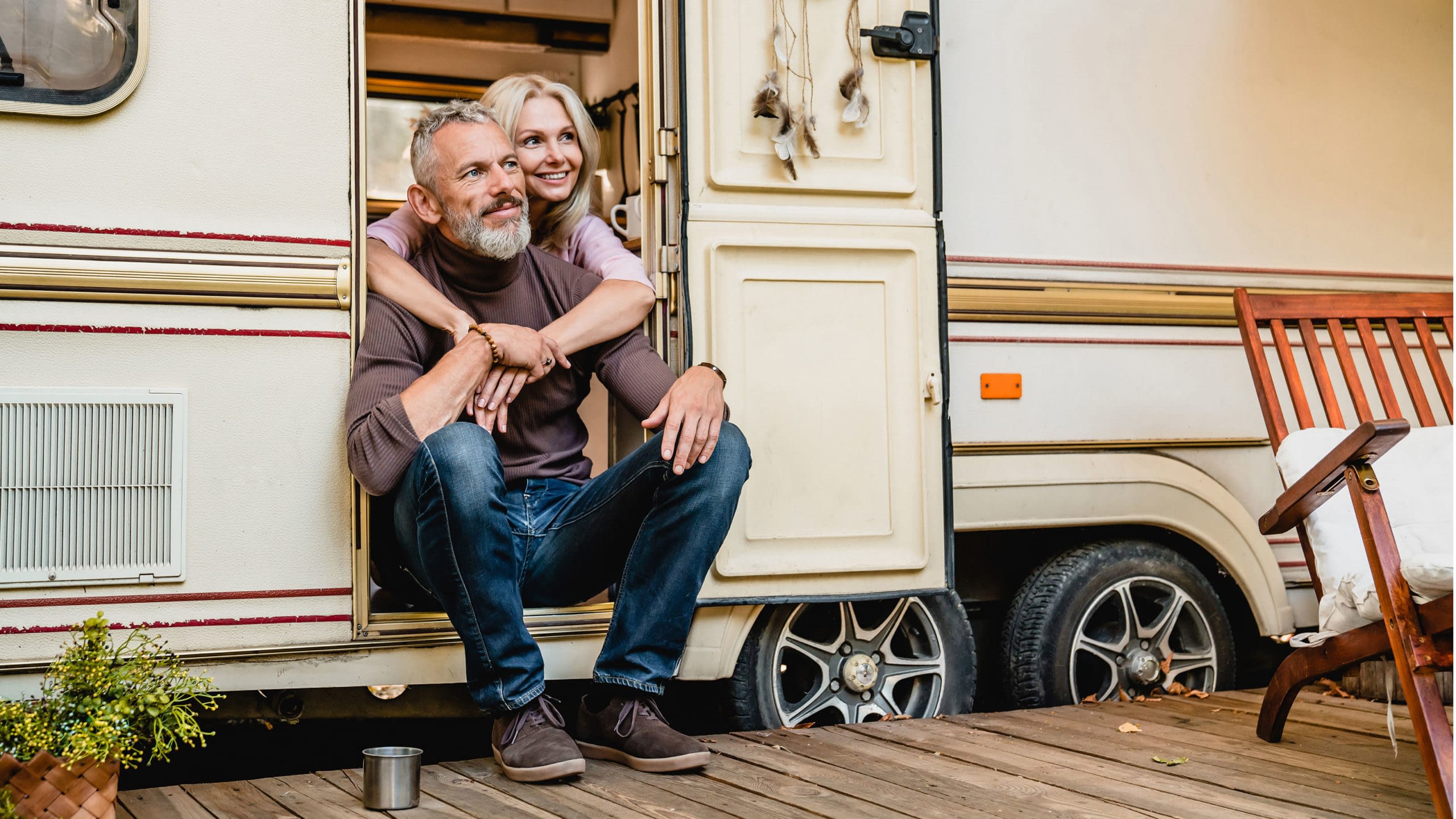 Happy couple sitting in the doorway of their motor home.