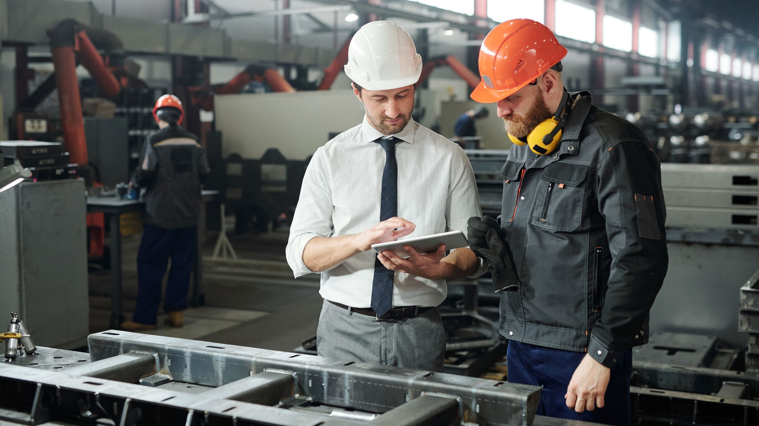 Foreman and worker in conversation at a manufacturing facility.