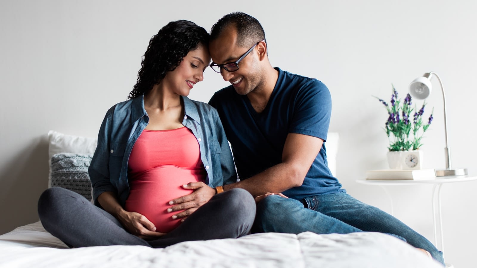 pregnant woman and man sitting on bed