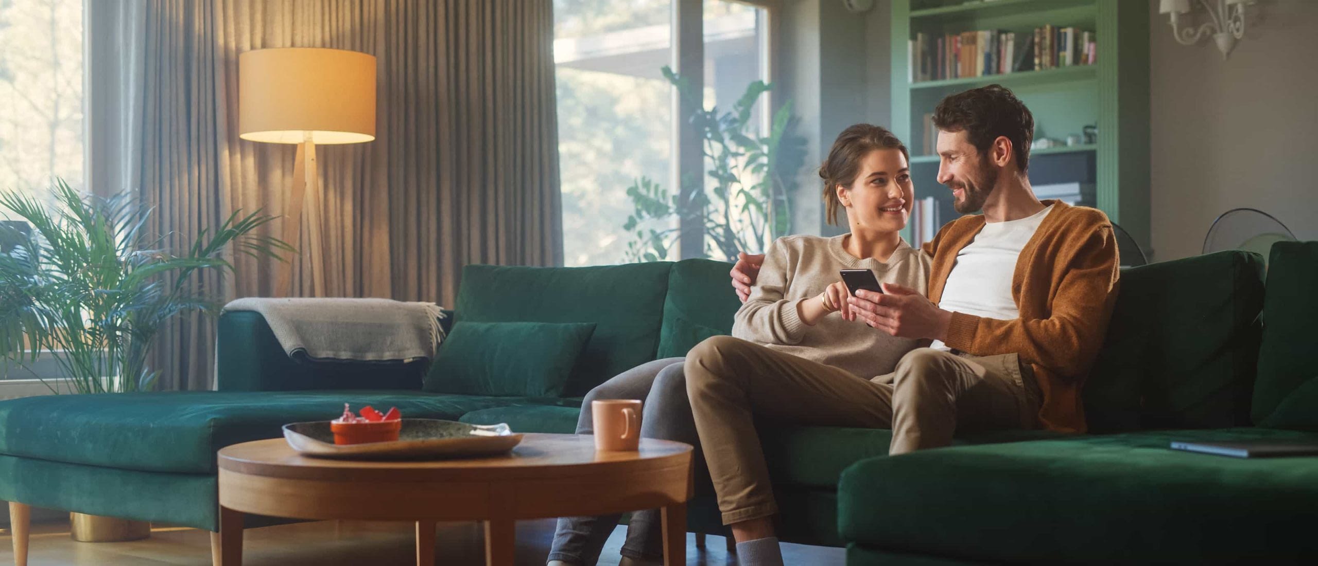 Couple-Sitting-On-Couch-Looking-At-Phone