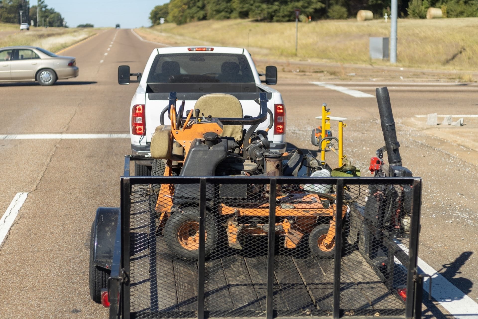 227 pickup truck hauling a trailer with a lawnmower in it