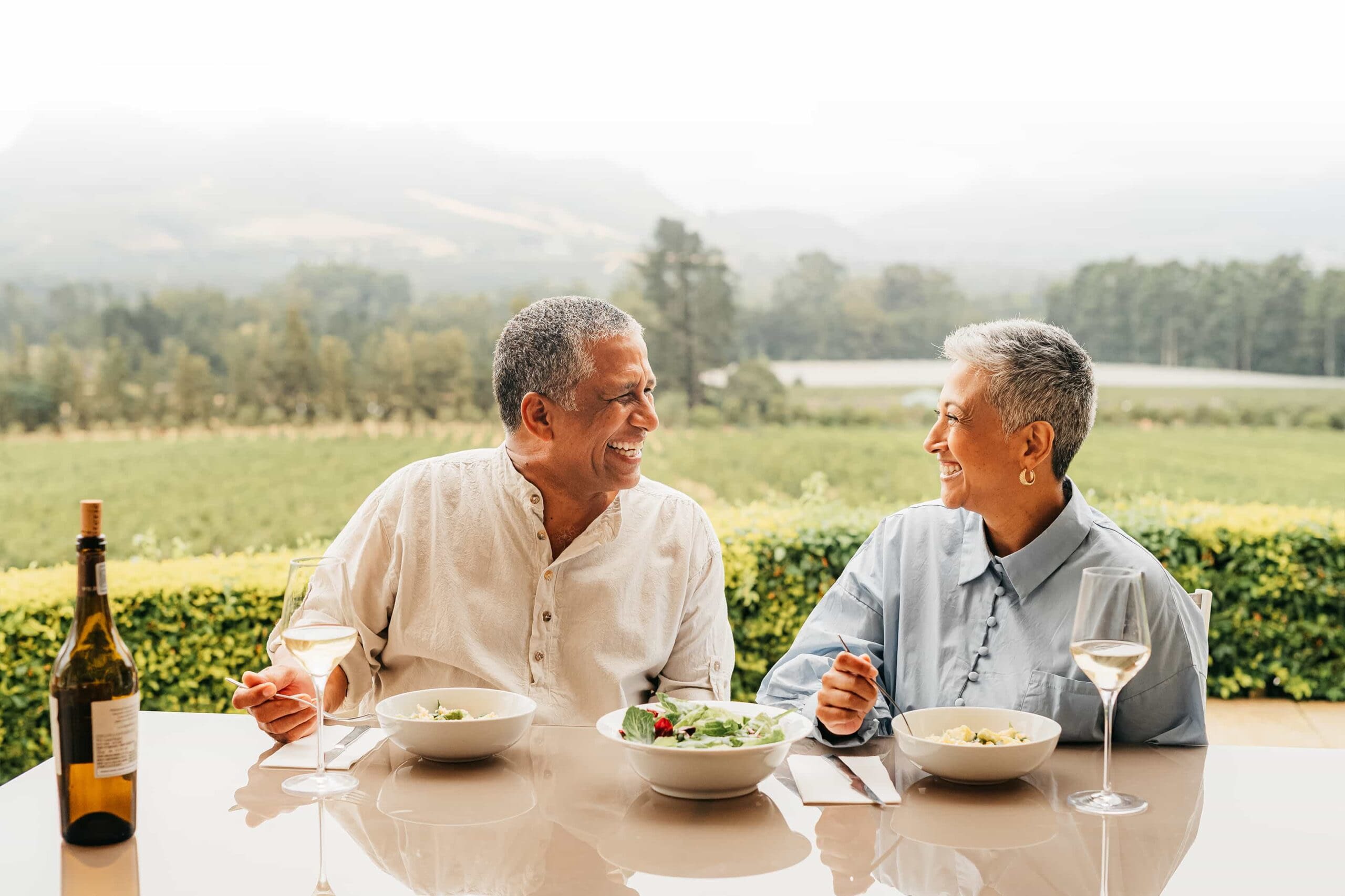 GettyImages-1425127461 Senior couple eating food on vineyard, lunch at wine farm during holiday in Italy for retirement and luxury vacation in the country side.