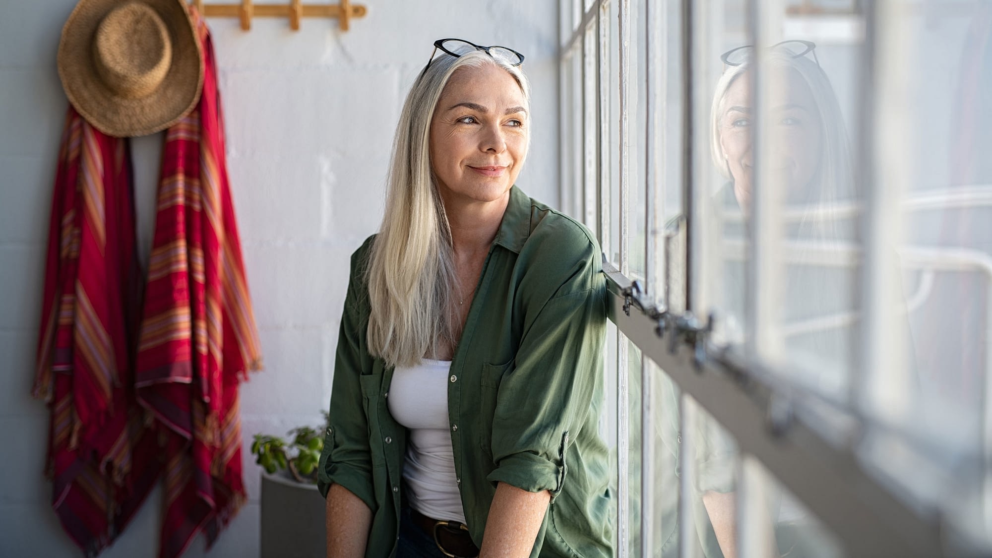 Mature women sitting contentedly looking out a window.