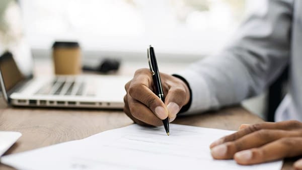 Business man signing document, hand holding pen putting signature at paper Business man signing an official document