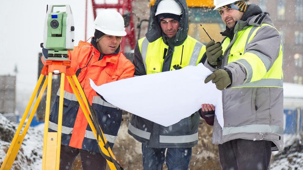Civil Engineers At Construction Site In Winter Season Civil engineers at construction site are inspecting ongoing works according to design drawings in difficult winter conditions