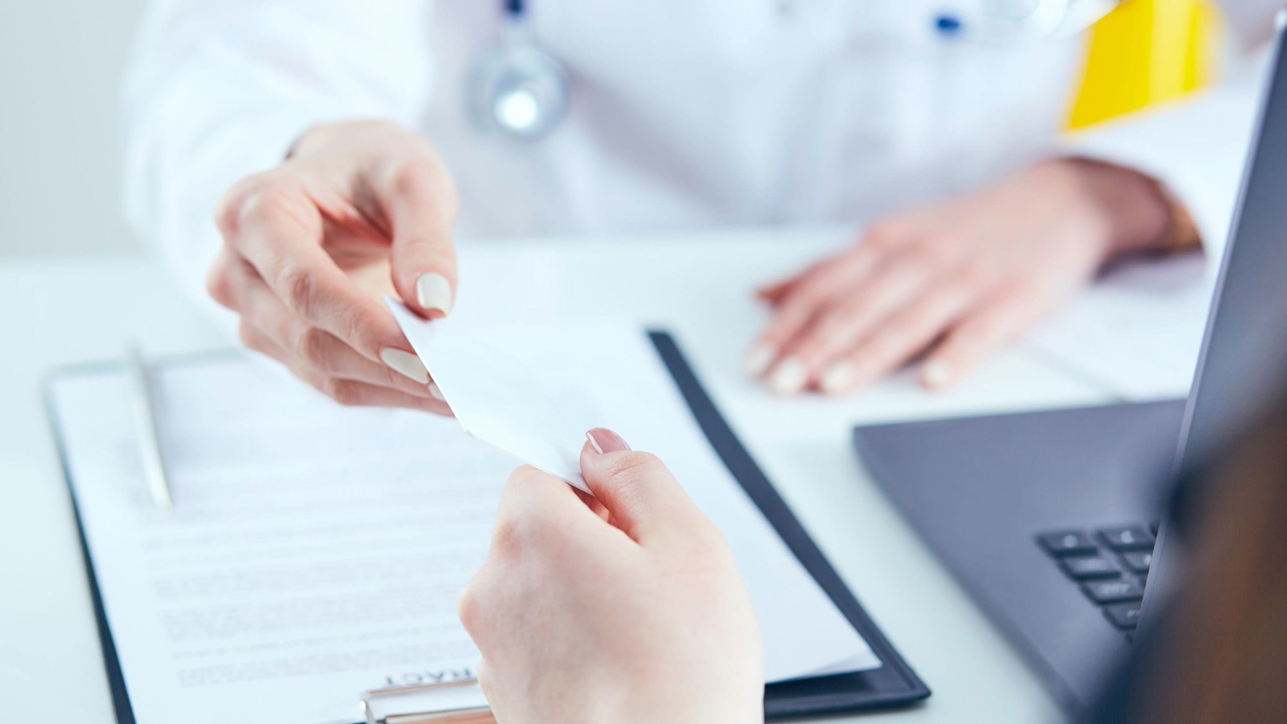 Close up of person's hand presenting health insurance card to health care worker.