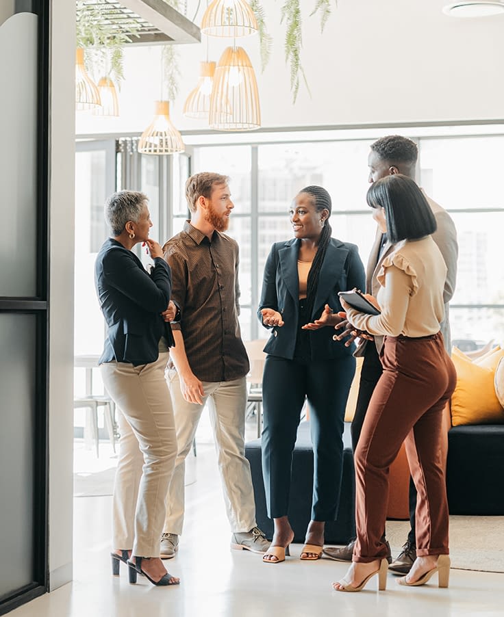 HPContent Corporate team standing in a company lounge having discussion about creative project. Diversity, staff and professional people planning meeting in office building. Work friends having a conversation.