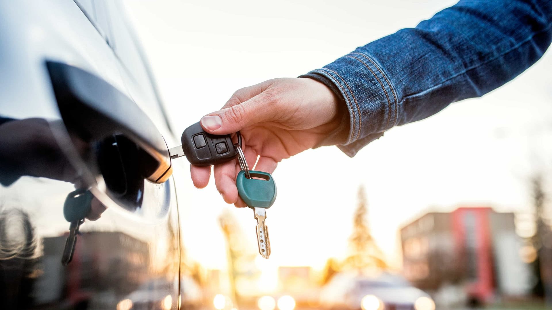 Close up of a person's arm unlocking a car door.