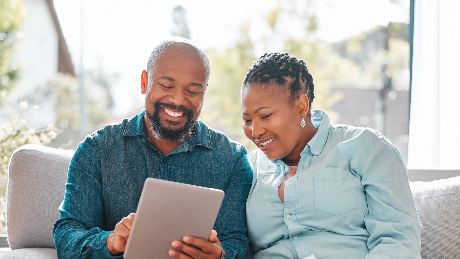 Mature couple reviewing retirment planning documents on tablet.