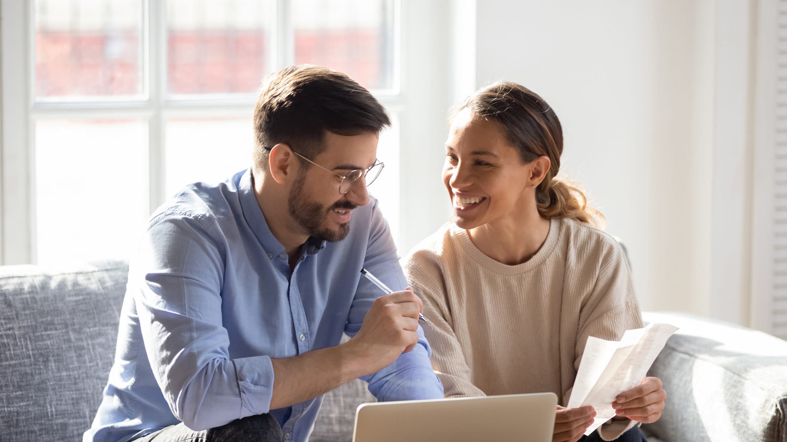 Happy couple looking at laptop and documents.