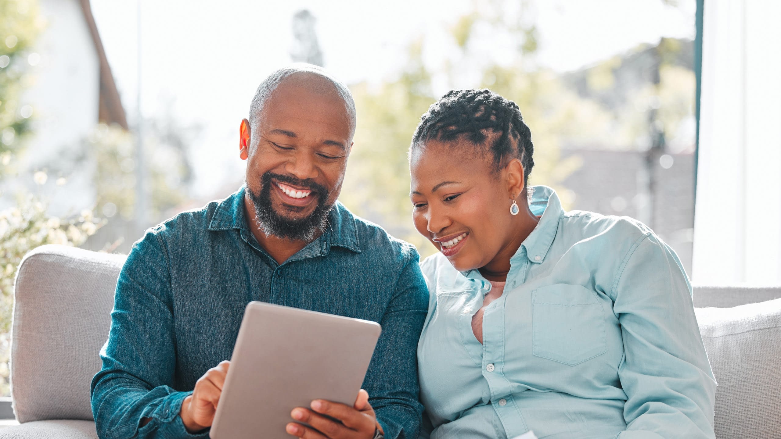 Mature couple reviewing retirment planning documents on tablet.