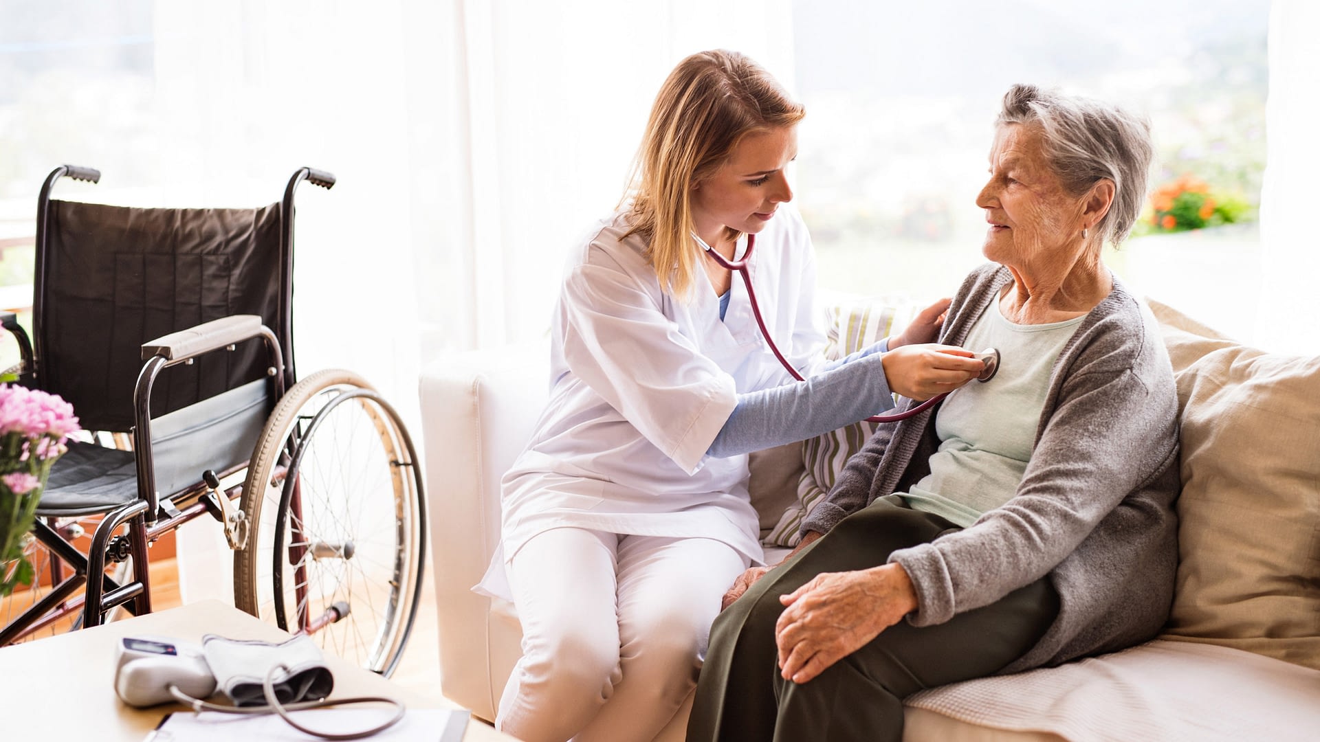 Health care worker examining senior patient during a home visit.