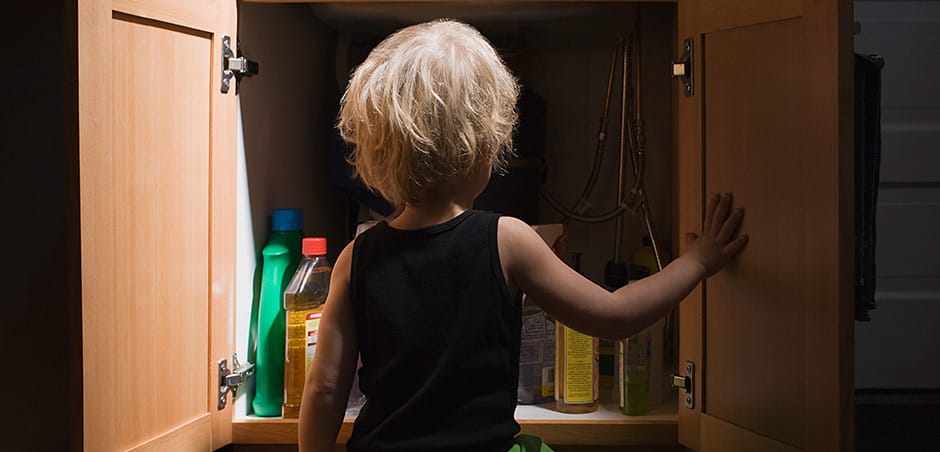 Child Standing In Front Of Cleaning Product Bottles