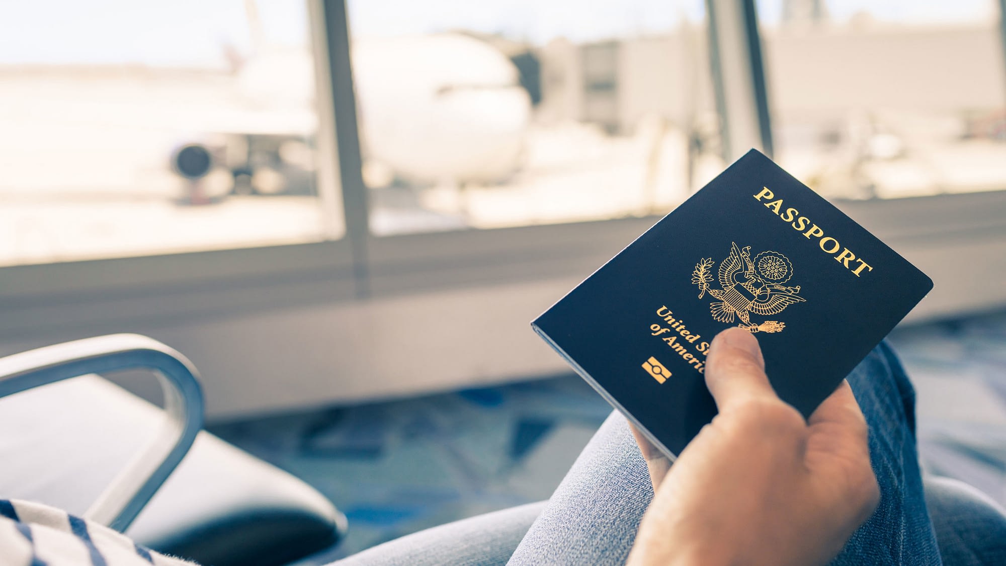 Close up of person's hand holding a passport while at the airport.