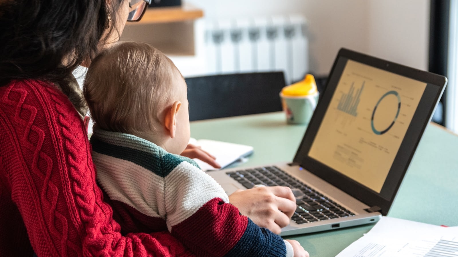 mother holding baby while working on computer