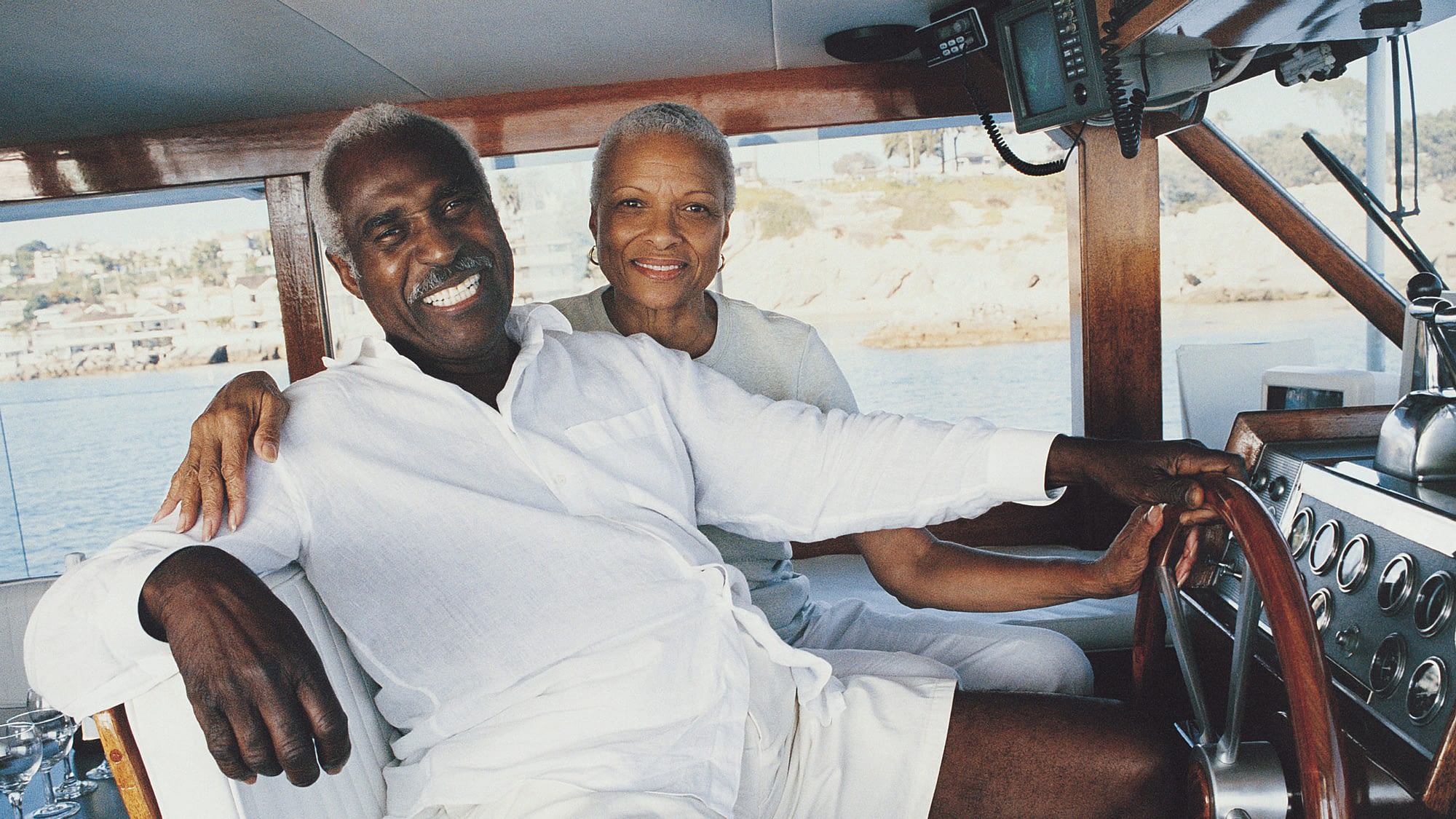 Retired couple sitting at the helm of a luxury yacht.