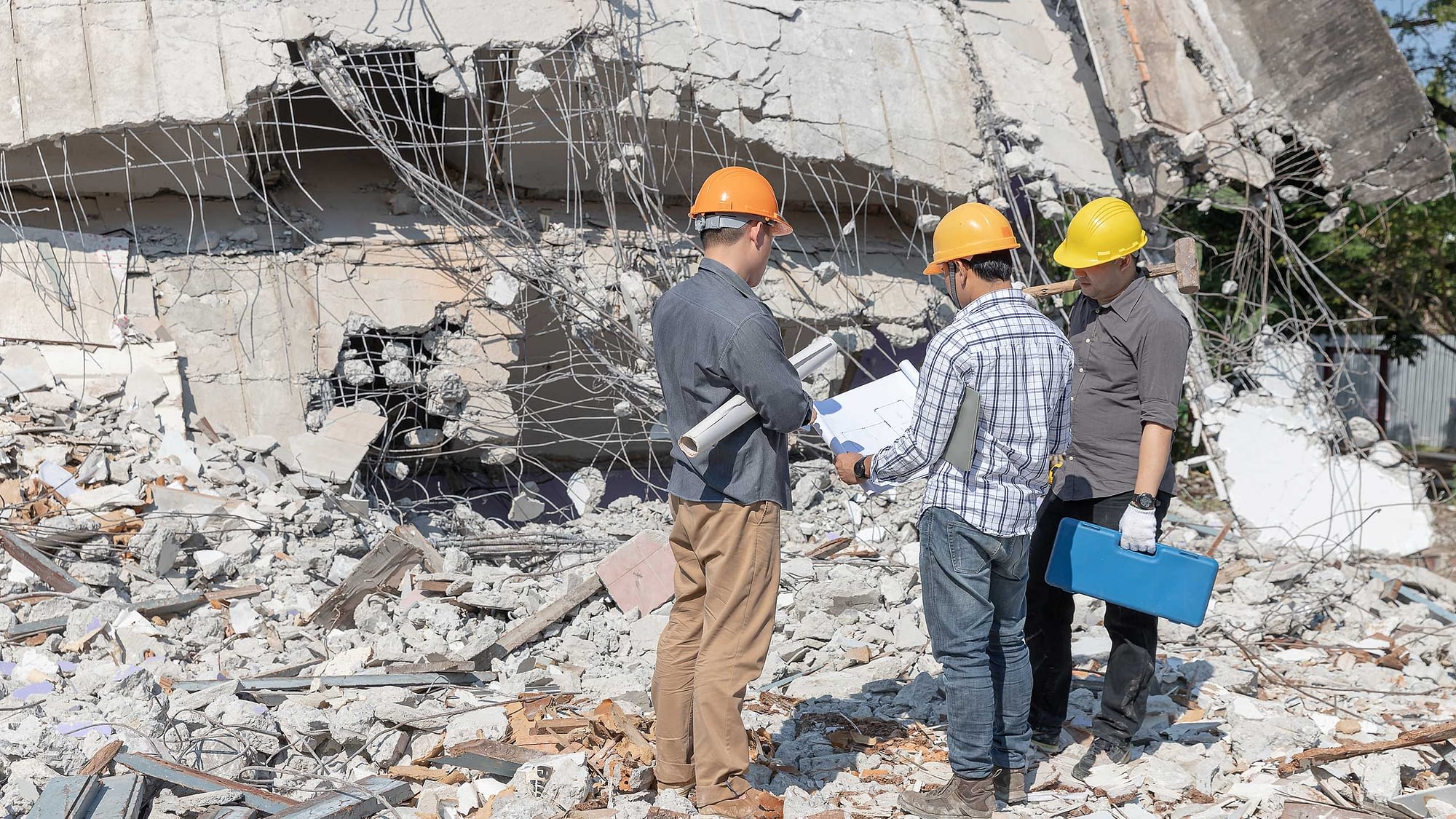Three construction workers assessing damage to building from earthquake.