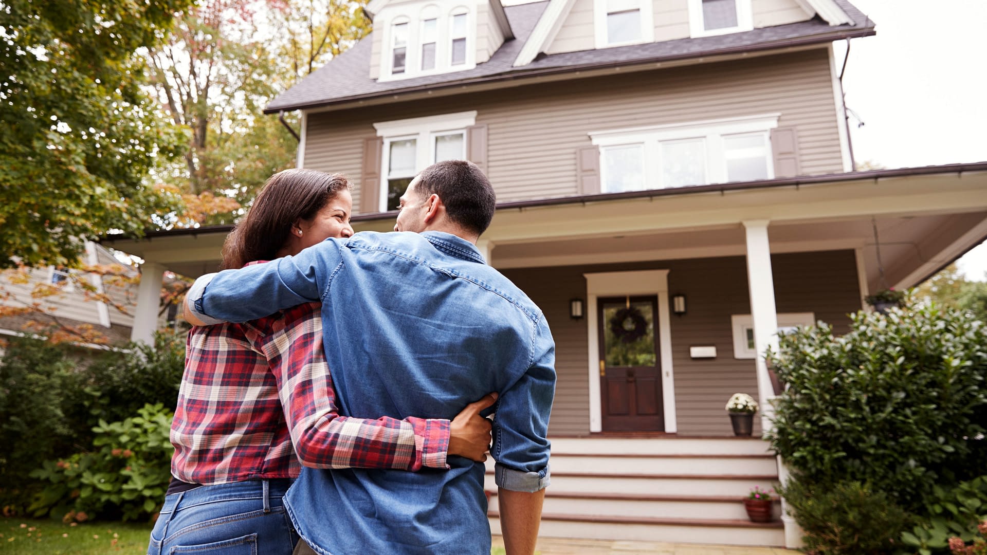 A couple hugging while walking towards their house.