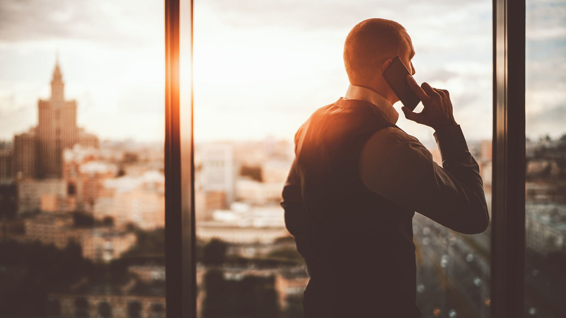 Businessman on phone while looking out the window of a high rise office.