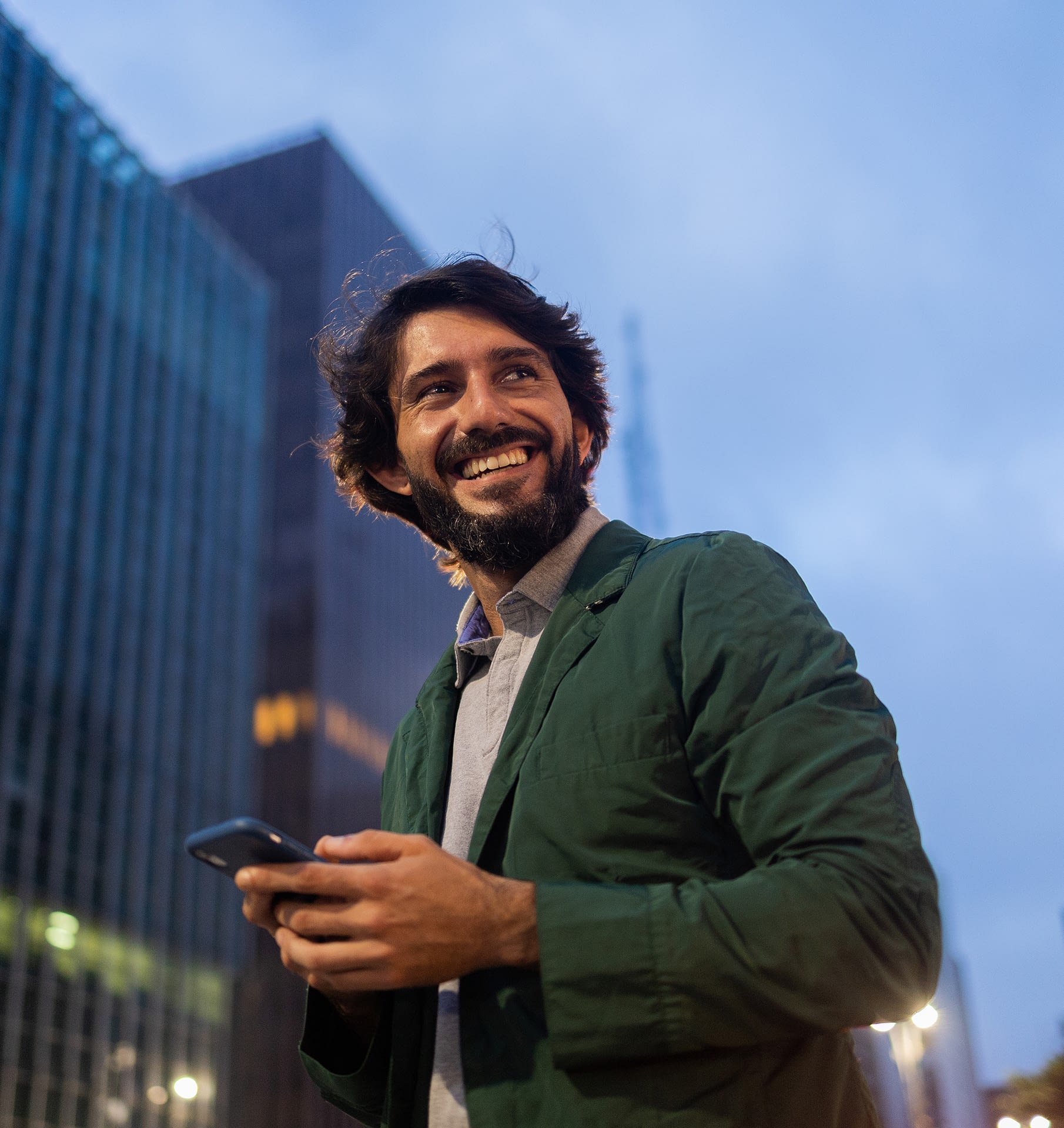 View-of-young-man-using-a-smartphone-at-night-time-with-city-view-landscape-in-the-background