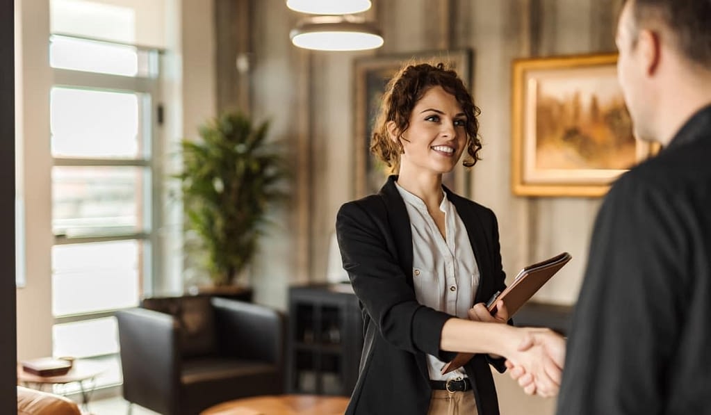 Professional woman shaking hands with a man while they meet in her office