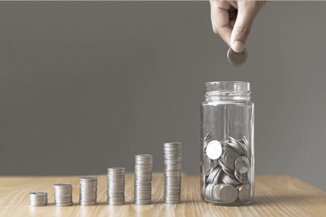 A person dropping a coin into a coin jar