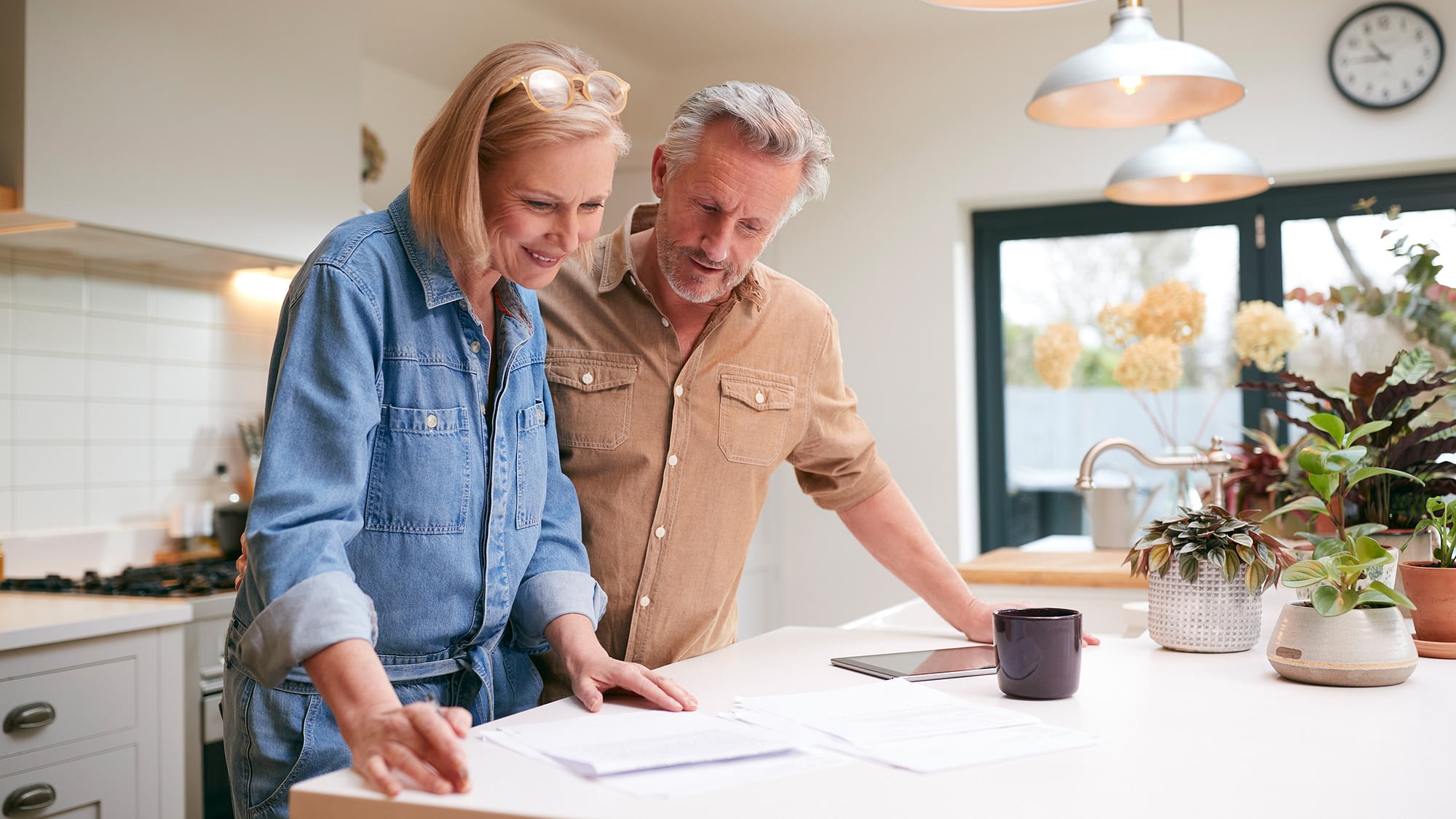 Mature couple reviewing universal life paperwork in their kitchen.