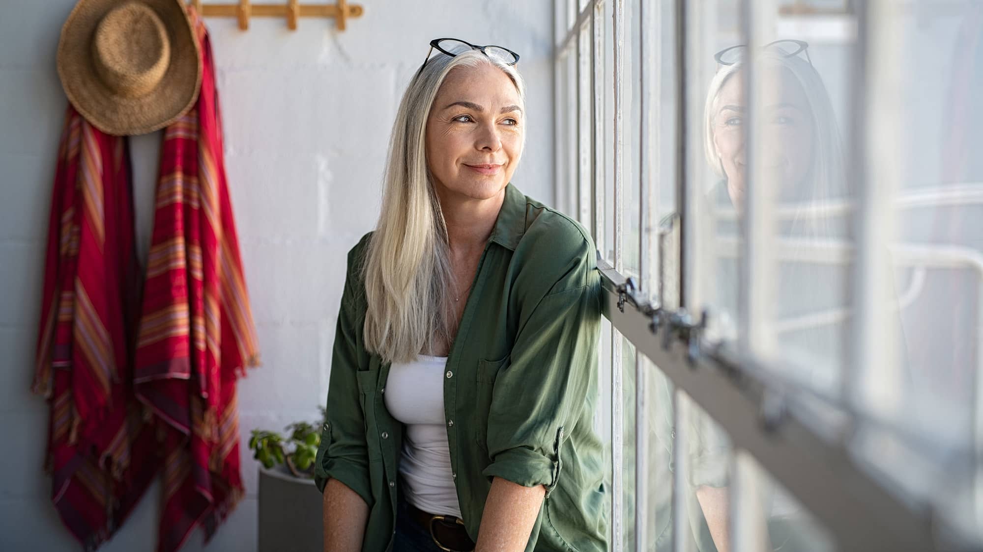 Mature women sitting contentedly looking out a window.