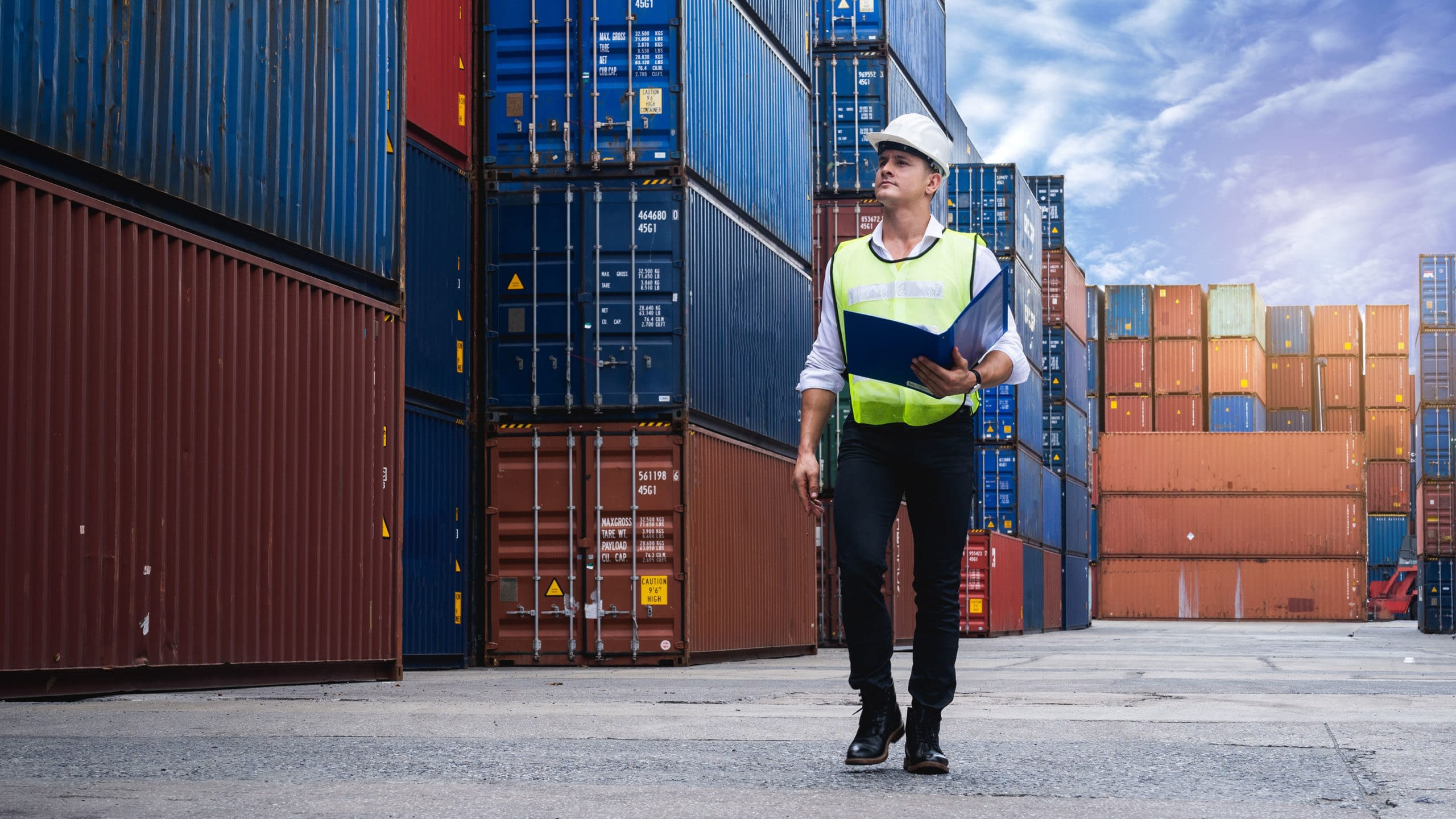 Man walking through large stacks of cargo containers.