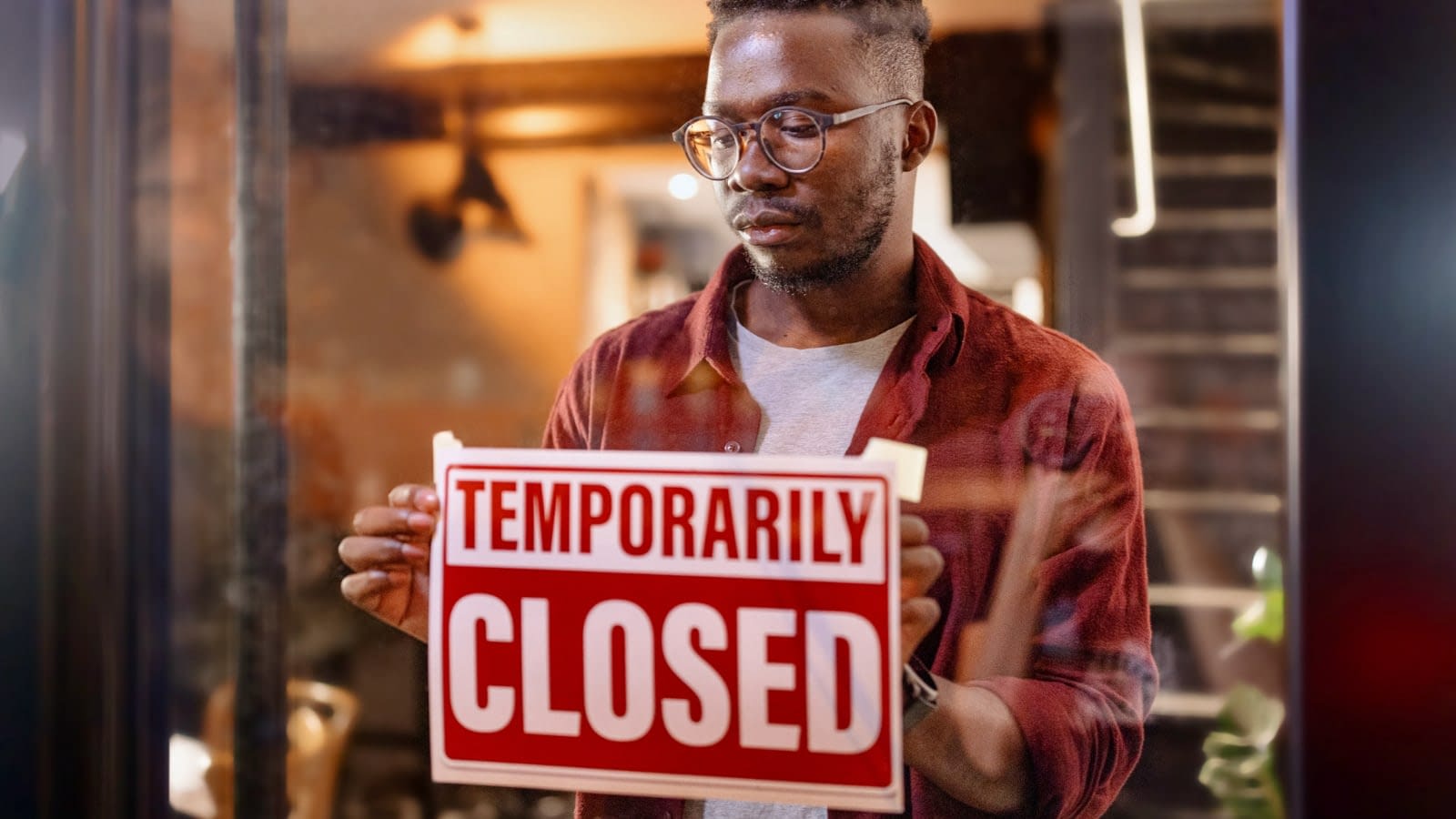 August 19 Business owner putting up sign on store that says temporarily closed