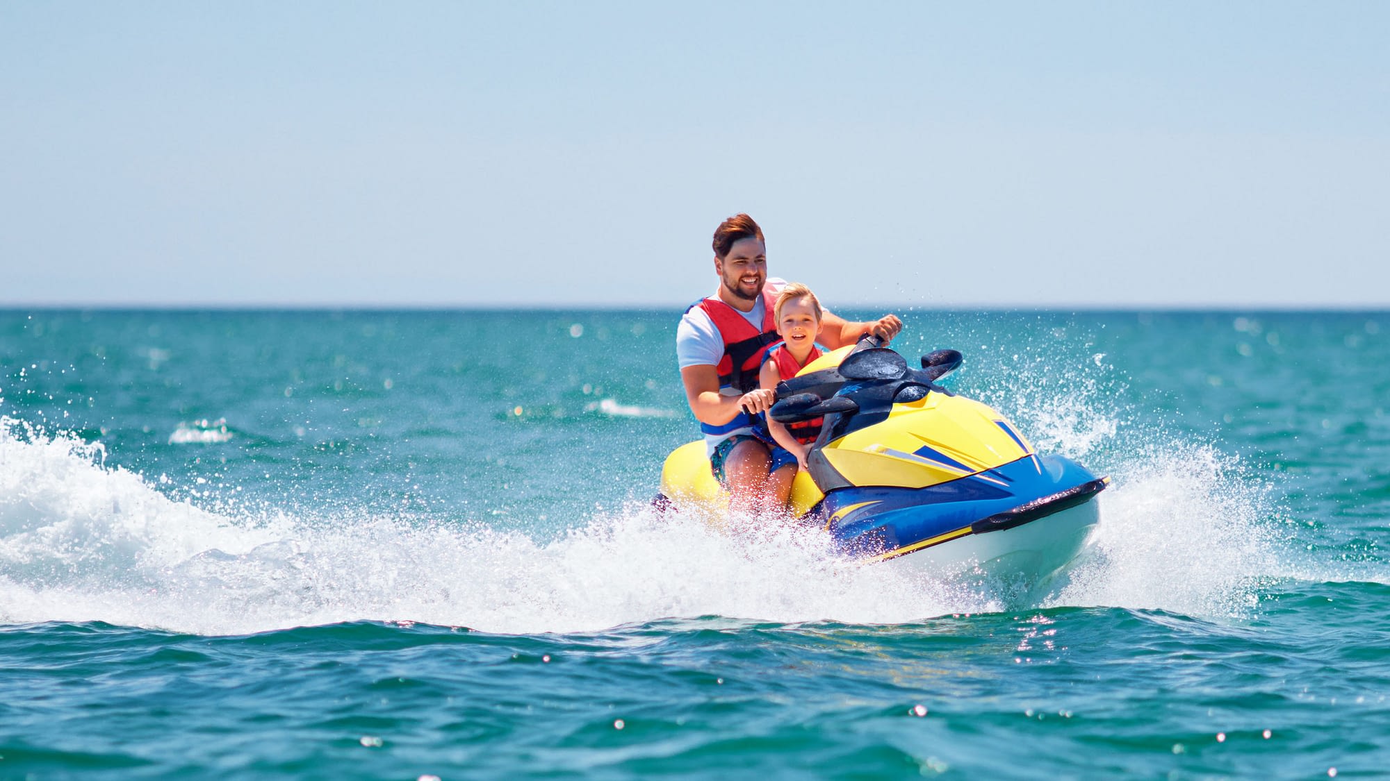 Father and son riding a jet ski.