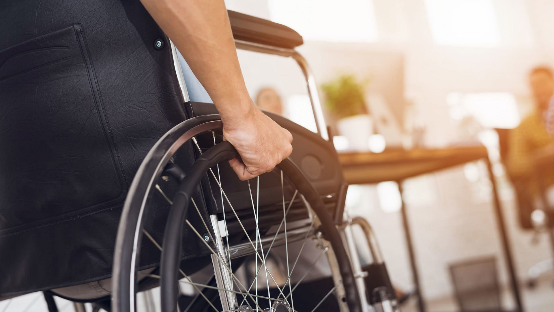 Closeup of the side of a wheelchair and person's arm.