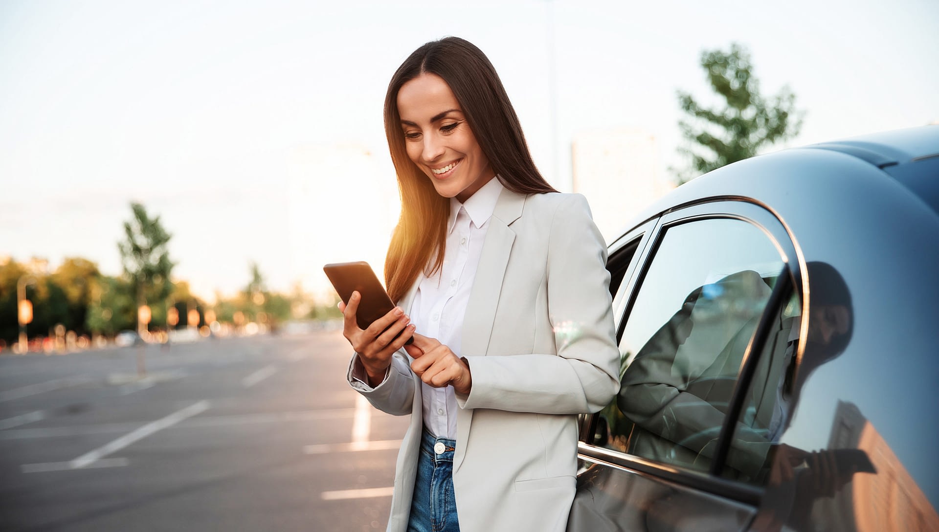 woman-standing-next-to-car-looking-at-phone