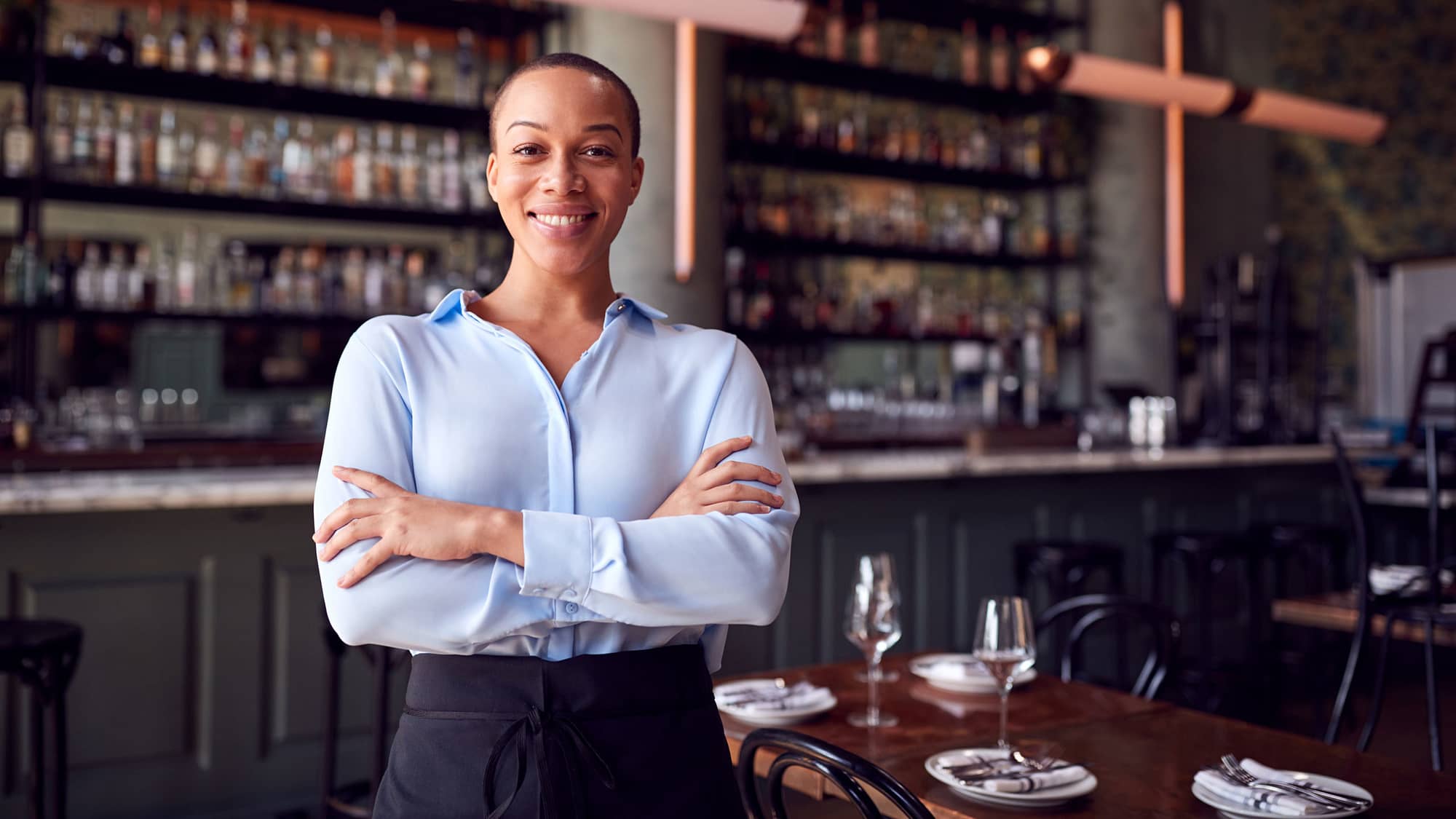 Restaurant owner standing proudly in front of tables and bar.